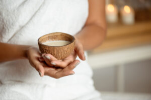 Close up photo of girl holding coconut in spa salon. Copy space.